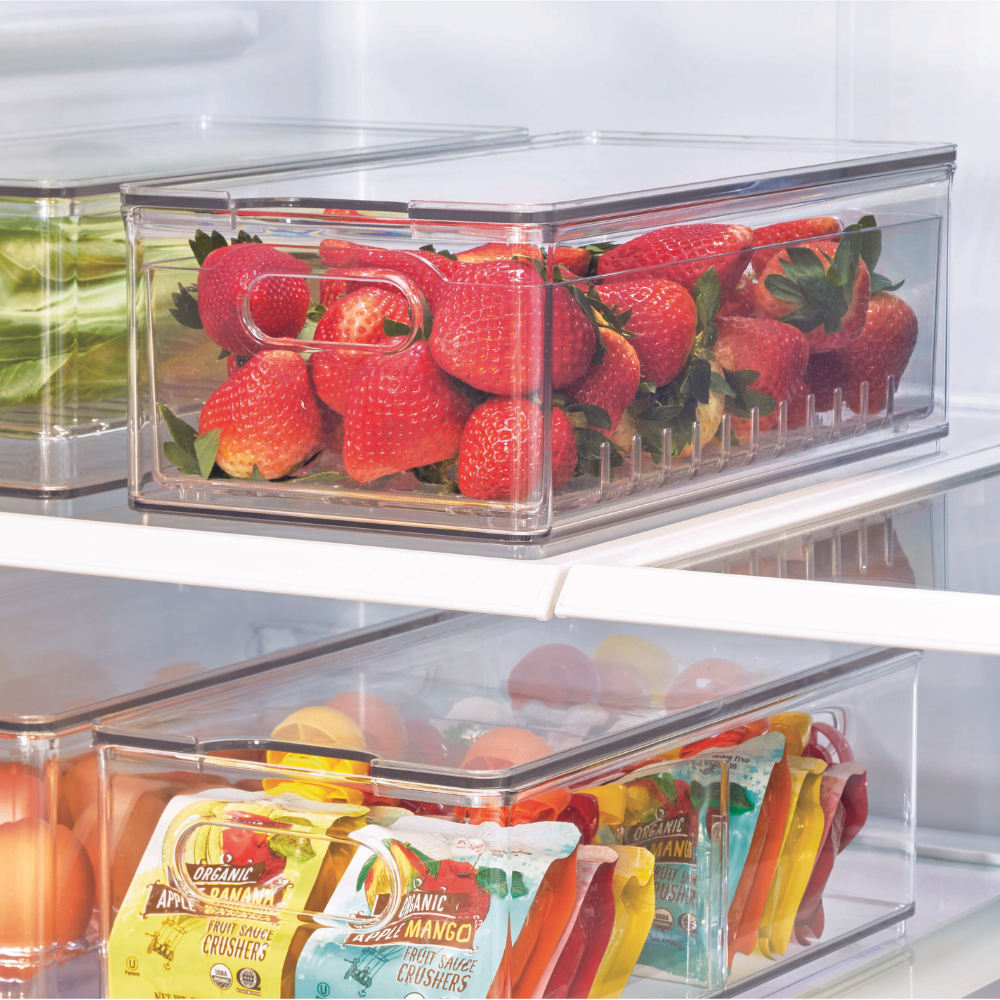 Erdbeeren liegen in einem durchsichtigen Behälter im Kühlschrank neben anderen Lebensmitteln.