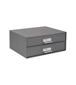 Graue Pappschubladenbox mit Metallschildern zur Organisation im Büro.