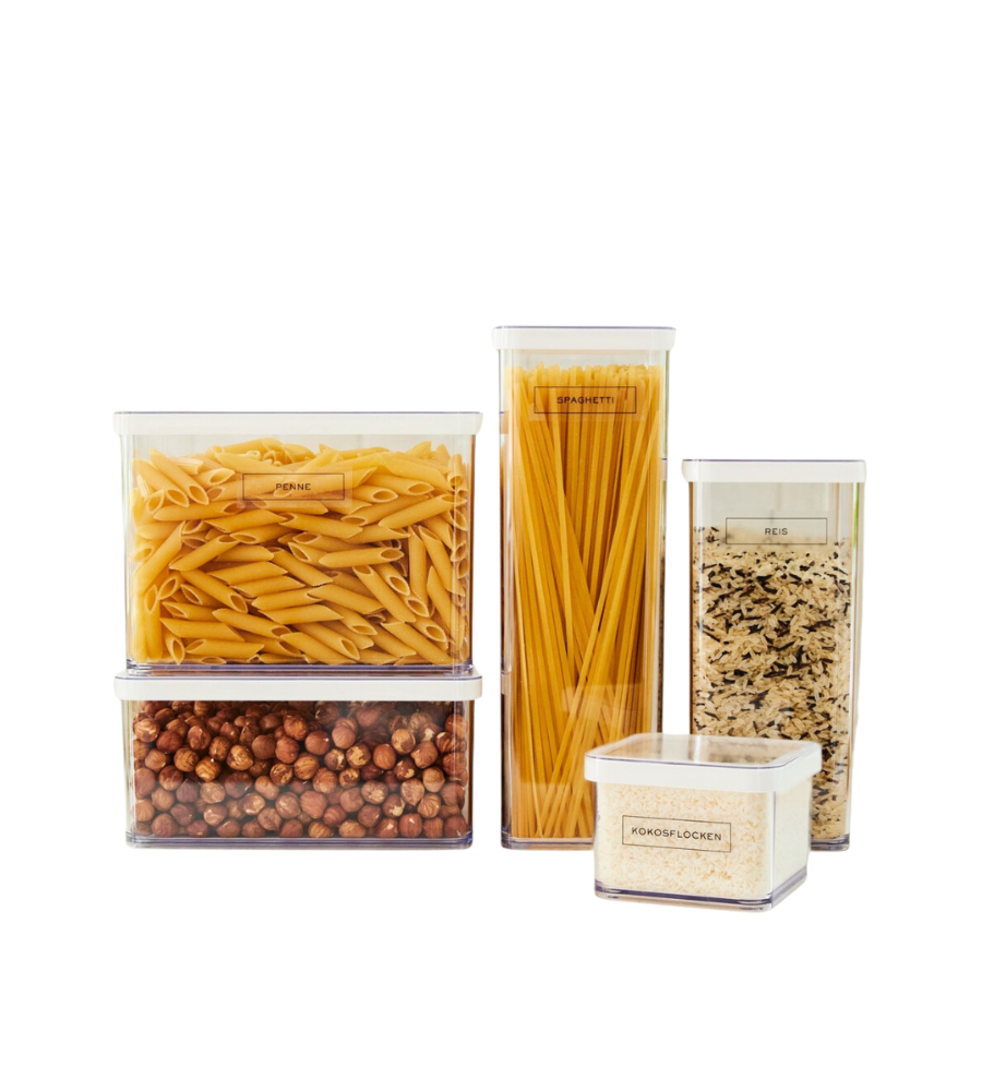 Fünf klare, beschriftete Behälter mit Rotho LOFT Aufkleber - Küchenorganisation organisieren Penne, Spaghetti, Reis, Kichererbsen und kurze Nudeln auf weißem Hintergrund für eine aufgeräumte Küche.