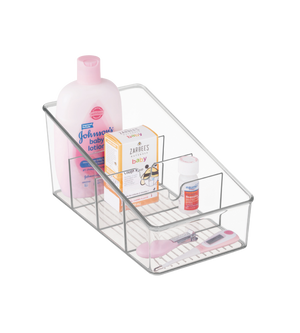 Ein iDesign LINUS - Aufbewahrungsbehälter KLAR mit Fächern hält Johnsons Babylotion, Zarbees Babyhustensaft, eine kleine Flasche und ein rosafarbenes digitales Thermometer, alles fein säuberlich auf einem weißen Hintergrund angeordnet.