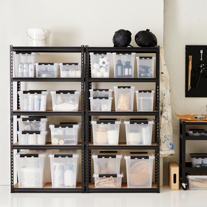 Zwei schwarze Metallregale enthalten durchsichtige Orthex SmartStore Box KLAR 31L, die BPA-frei und stapelbar sind und Haushaltsgegenstände enthalten. In der Nähe stehen ein Gerätewagen, eine Hängeschürze, ein Eimer und eine Stecktafel mit Werkzeugen vor einer weißen Wand.