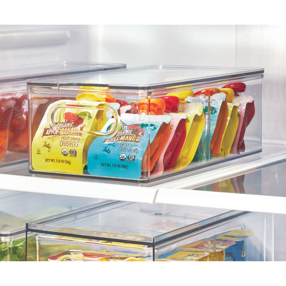 Der iDesign HOME EDIT Aufbewahrungsbehälter KLAR Fridge mit 2 Fächern und Deckel sorgt im Kühlschrank für ordentlich und aufrecht sortierte Bio-Apfelmusbeutel in verschiedenen Farben.